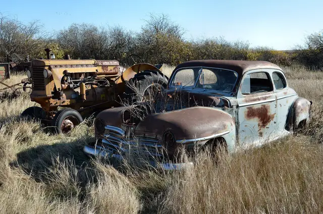 Old Plymouth car and tractor in a field
