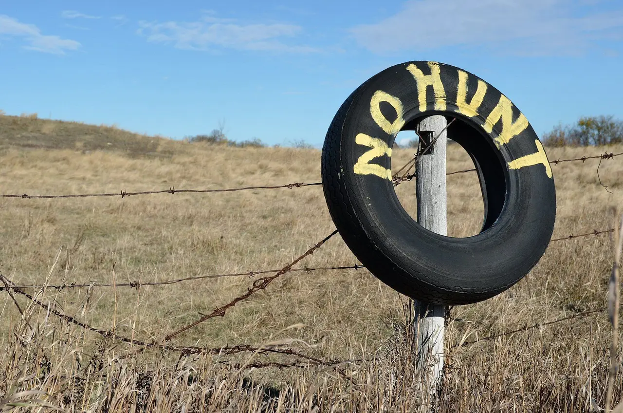 No hunting sign on a tire at a fence, 2011